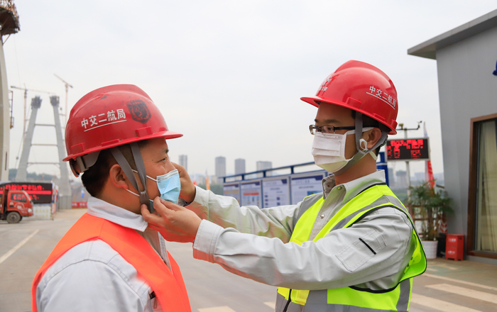 白居寺长江大桥项目党支部书记、工会主席李杰（右）在施工现场为同事纠正口罩戴法.jpg